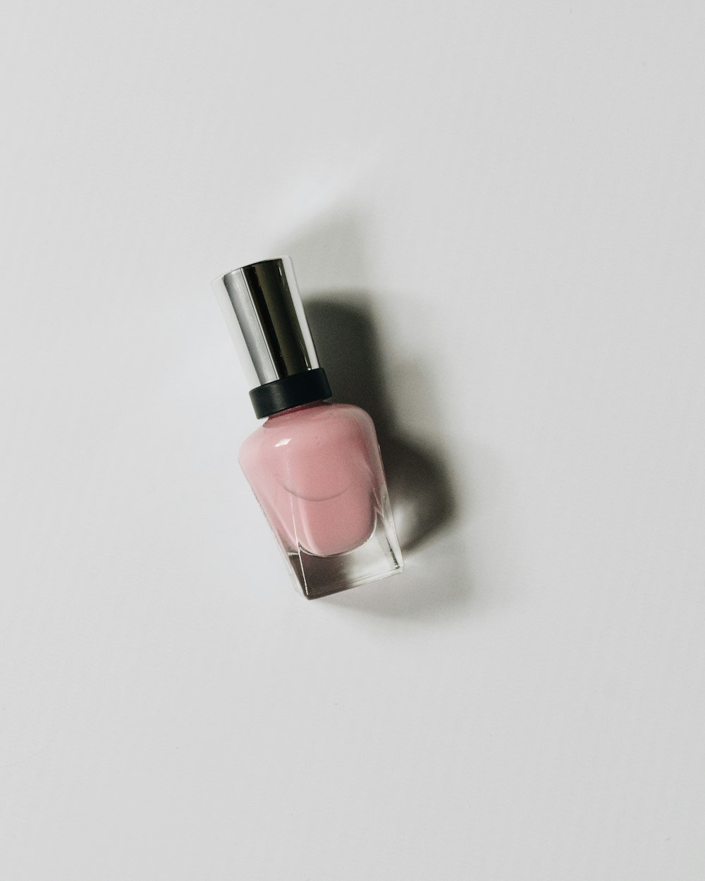 Pale pink nail polish bottle on a light background