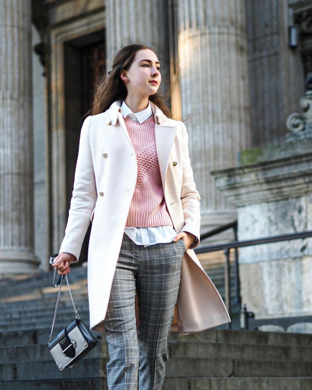 Woman in a pale coat carrying a crossbody bag