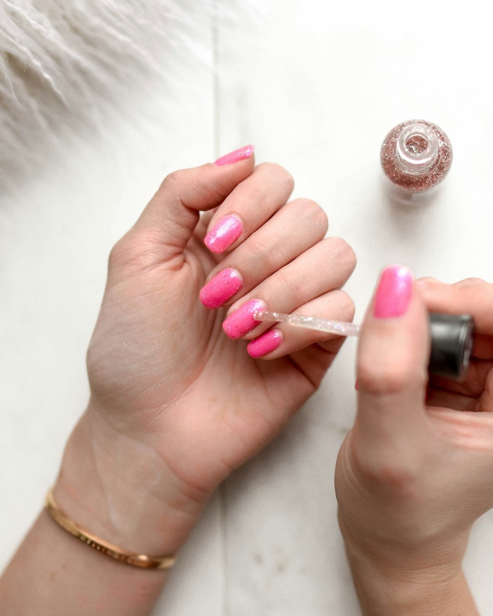 Glittered polish being applied to pink nails