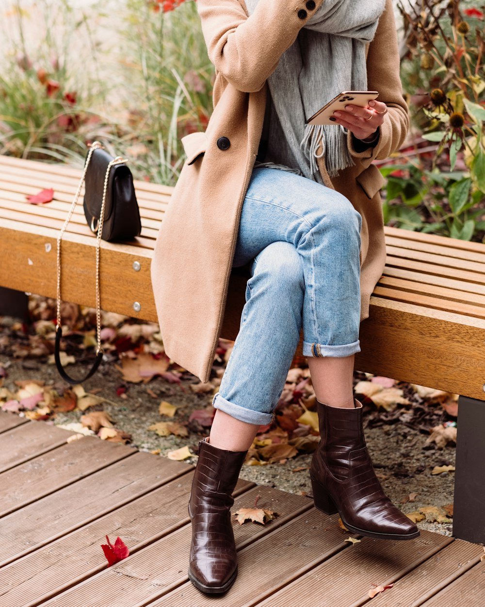 Woman sitting on a wooden bench in autumn clothing
