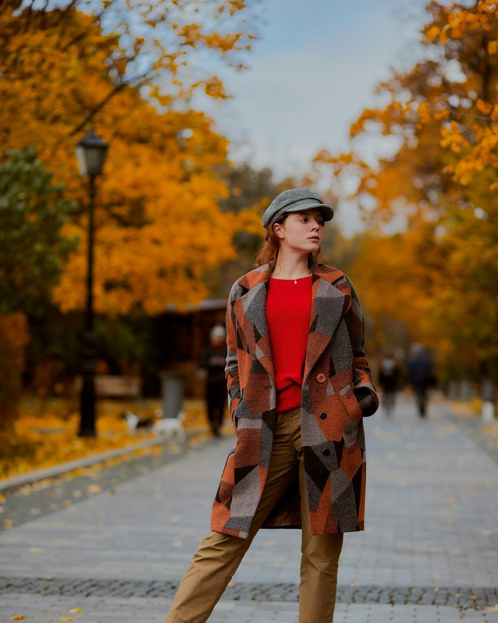 Woman standing in a park in transitional autumn layers