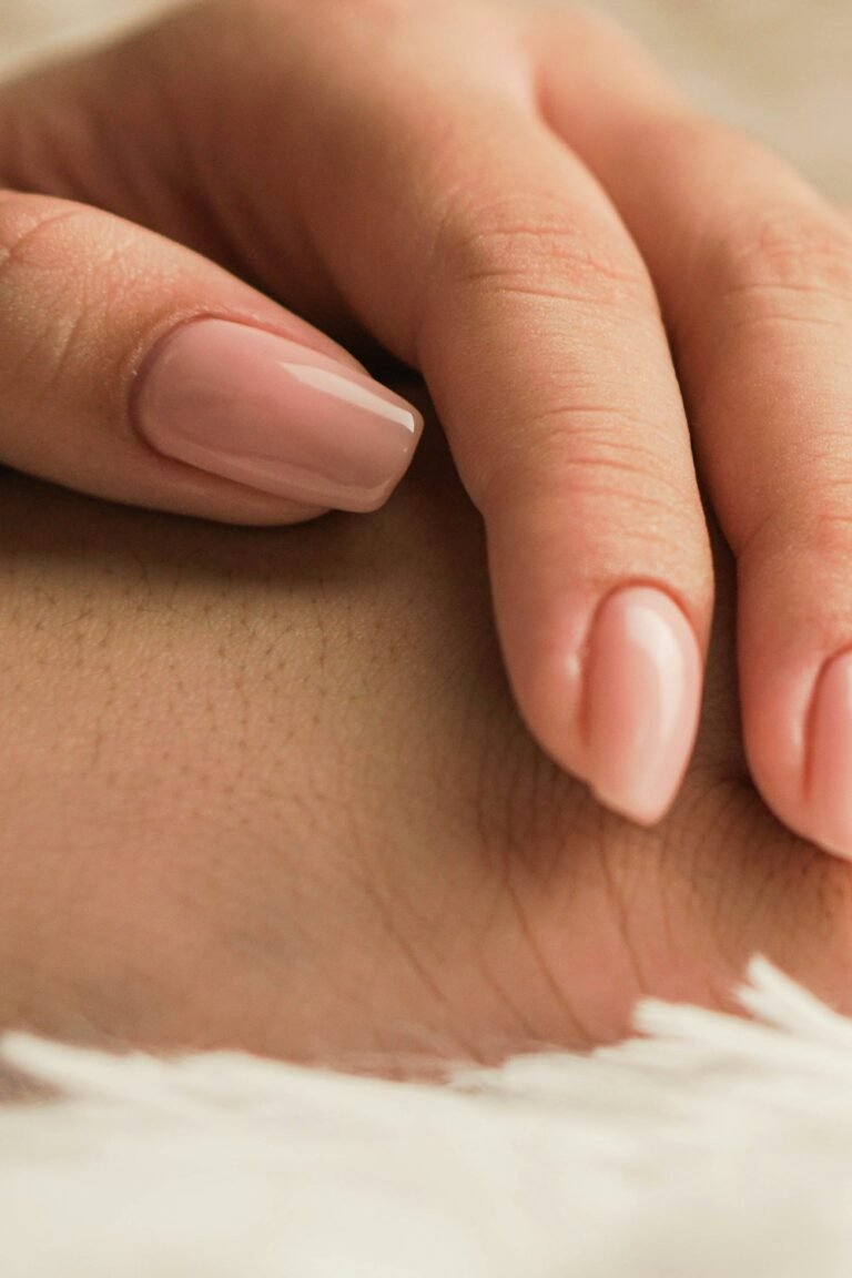 Short painted nails on a hand resting on white fabric
